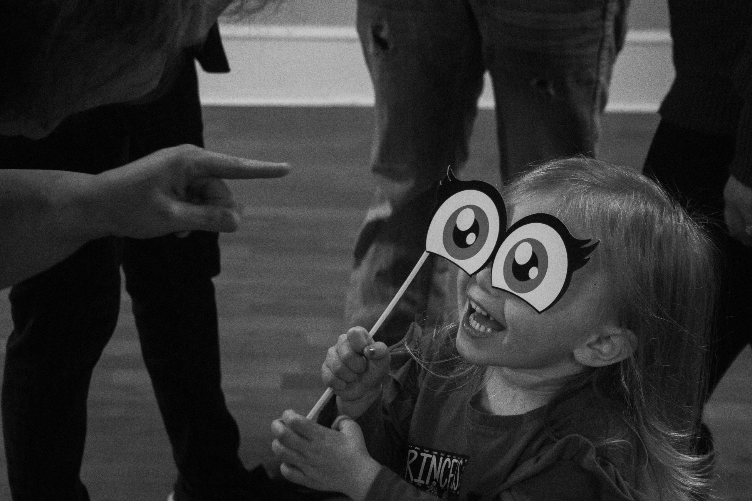 My mom points to my little cousin, who is playing with eyes meant for the photobooth at my grandma's 70th surprise party.